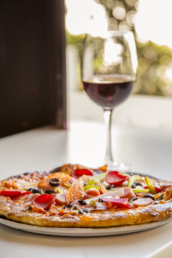 Pizza de carnes frías y vino tinto