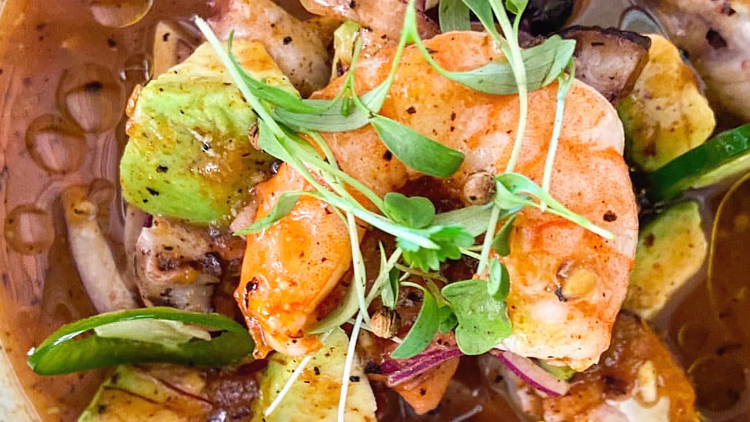 Un fresco coctel de mariscos con salsa de naranja y tomates rostizados