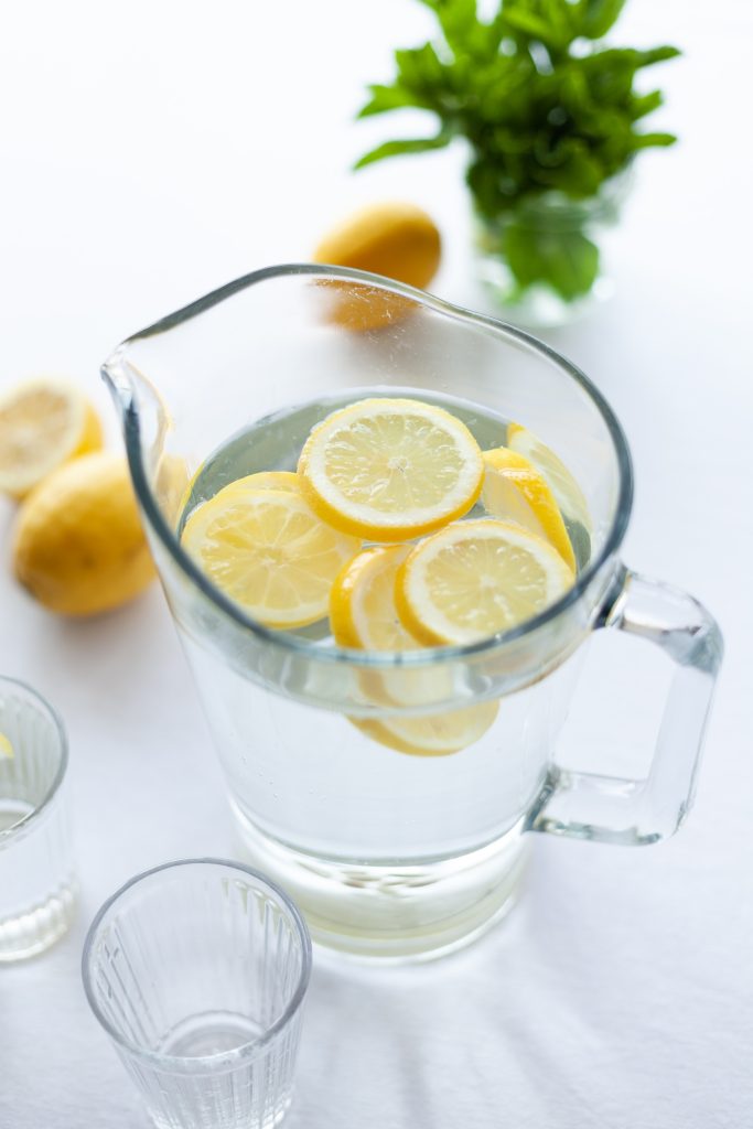 jarra de cristal con agua y rodajas de limón amarillo 